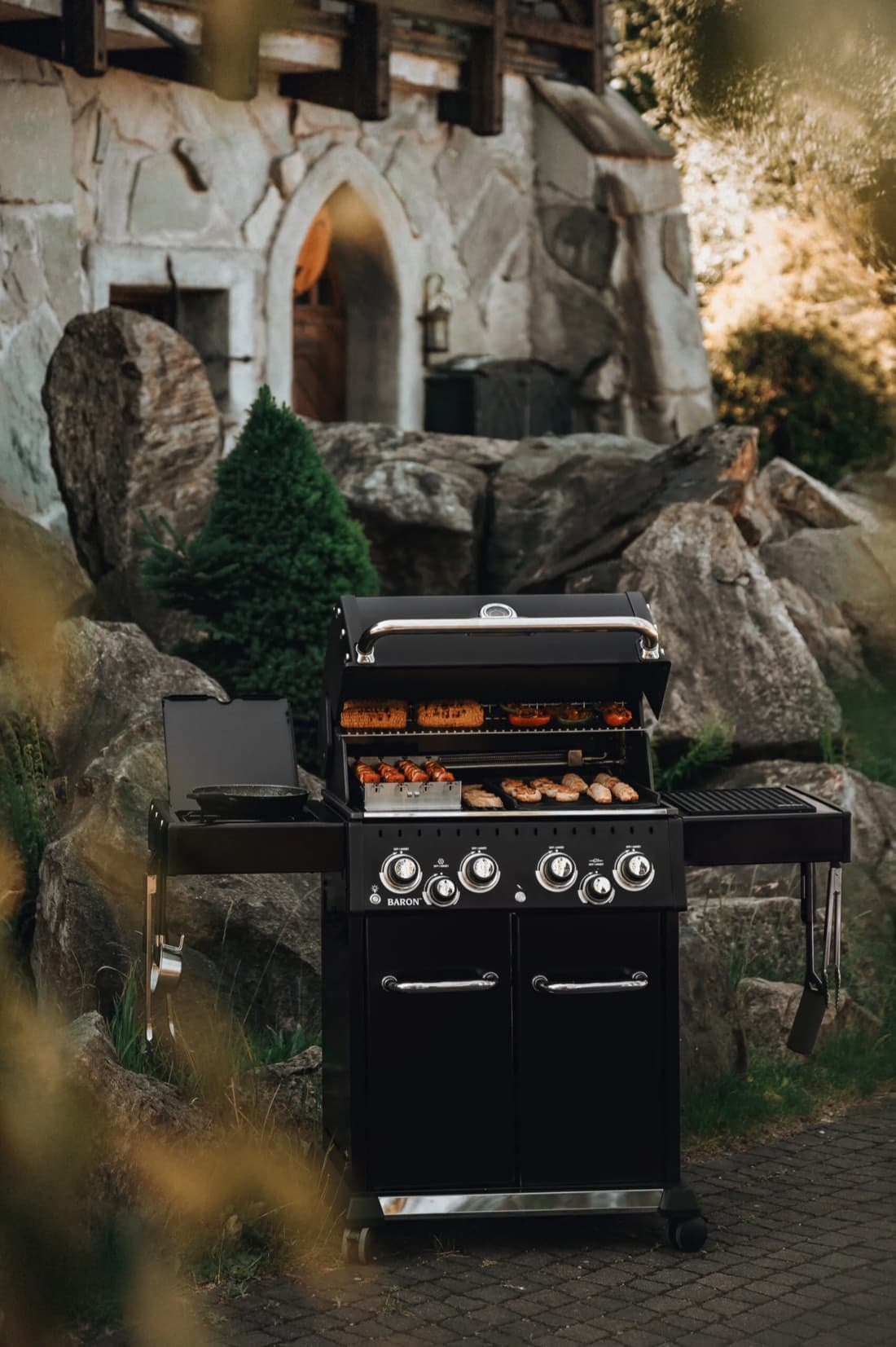 Barbecue a gas Broil King in un giardino con muro in pietra — cucine esterne e barbecue